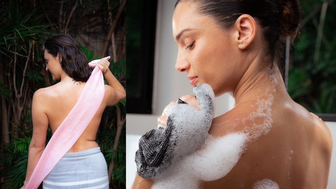 Woman using a pink Sima Japanese exfoliating towel across her back outdoors, and lathering her shoulder with a black Sima towel in the bath