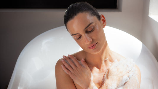 Woman relaxing in a warm bath with her hand resting on her shoulder