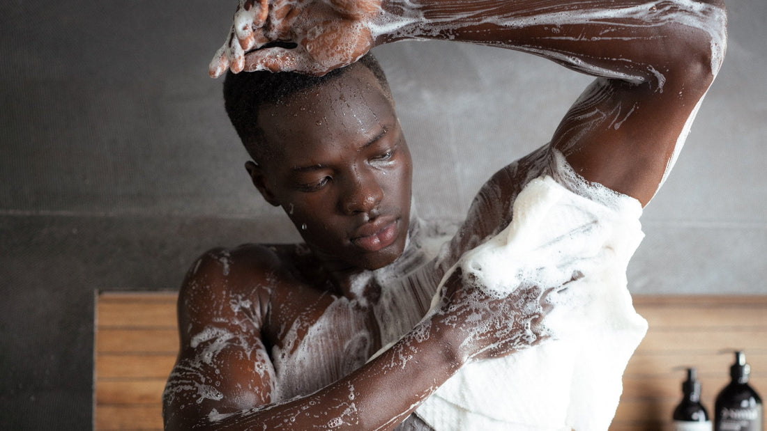 Man in the shower lathering his shoulder and back with a white Sima Japanese exfoliating towel