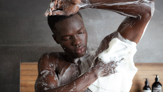 Man in the shower lathering his shoulder and back with a white Sima Japanese exfoliating towel