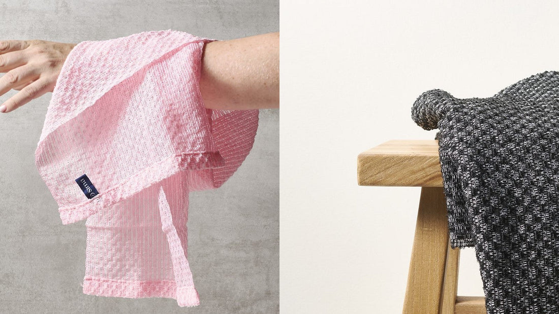 Pink Sima Japanese exfoliating towel draped over a forearm beside a black towel on a wooden stool